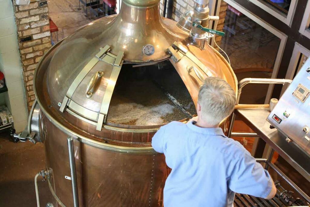 Man tending beer brewing process.